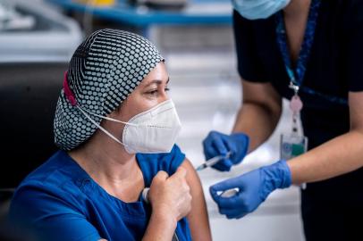  In this handout picture released by Chiles Presidency, Chilean nurse Zulema Riquelme receives the first of two Pfizer/BioNTech Covid-19 vaccine jabs, at the Metropolitano Hospital in Santiago, on December 24, 2020. - A flight carrying 10,000 vaccines produced by Pfizer/BioNTech arrived at Santiago airport in the Chilean capital on Thursday morning. (Photo by marcelo segura / CHILES PRESIDENCY / AFP) / RESTRICTED TO EDITORIAL USE - MANDATORY CREDIT AFP PHOTO / CHILES PRESIDENCY / Marcelo SEGURA  - NO MARKETING - NO ADVERTISING CAMPAIGNS - DISTRIBUTED AS A SERVICE TO CLIENTSEditoria: HTHLocal: SantiagoIndexador: MARCELO SEGURASecao: diseaseFonte: CHILES PRESIDENCYFotógrafo: Handout<!-- NICAID(14676653) -->