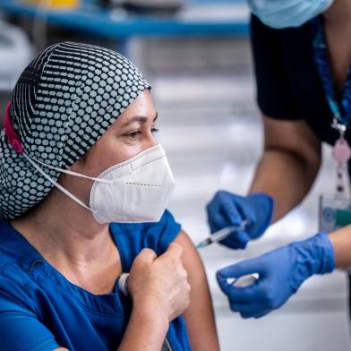  In this handout picture released by Chiles Presidency, Chilean nurse Zulema Riquelme receives the first of two Pfizer/BioNTech Covid-19 vaccine jabs, at the Metropolitano Hospital in Santiago, on December 24, 2020. - A flight carrying 10,000 vaccines produced by Pfizer/BioNTech arrived at Santiago airport in the Chilean capital on Thursday morning. (Photo by marcelo segura / CHILES PRESIDENCY / AFP) / RESTRICTED TO EDITORIAL USE - MANDATORY CREDIT AFP PHOTO / CHILES PRESIDENCY / Marcelo SEGURA  - NO MARKETING - NO ADVERTISING CAMPAIGNS - DISTRIBUTED AS A SERVICE TO CLIENTSEditoria: HTHLocal: SantiagoIndexador: MARCELO SEGURASecao: diseaseFonte: CHILES PRESIDENCYFotógrafo: Handout<!-- NICAID(14676653) -->