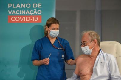  Doctor Antonio Sarmento receives a first dose of the Pfizer-BioNTech Covid-19 vaccine on December 27, 2020, at Sao Joao Hospital in Porto. - Less than a week after the green light for the Pfizer-BioNtech vaccine, several European Union states including Portugal, Italy, Spain and France, some severely affected by the pandemic, began their vaccination campaigns today against the coronavirus, following in the footsteps of many other countries. (Photo by MIGUEL RIOPA / AFP)Editoria: HTHLocal: PortoIndexador: MIGUEL RIOPASecao: diseaseFonte: AFPFotógrafo: STR<!-- NICAID(14677420) -->