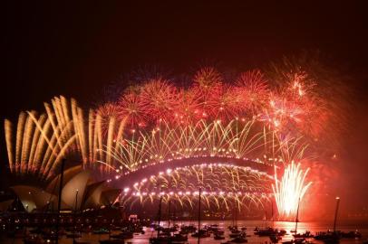  New Years Eve fireworks erupt over Sydneys iconic Harbour Bridge and Opera House (L) during the fireworks show on January 1, 2021. (Photo by SAEED KHAN / AFP)Editoria: LIFLocal: SydneyIndexador: SAEED KHANSecao: public holidayFonte: AFPFotógrafo: STF<!-- NICAID(14680887) -->