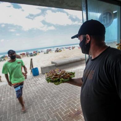 IMBÉ, RS, BRASIL - Matéria sobre dicas de como consumir alimentos e bebidas na beira da praia, durante a pandemia. (Foto: André Ávila/ Agência RBS)Na foto: Rodrigo Tochetto, 44 anos, dono do Quiosque do Rodrigo (de preto) e Deivid, funcionário do Quiosque do Rodrigo (de verde)<!-- NICAID(14681972) -->