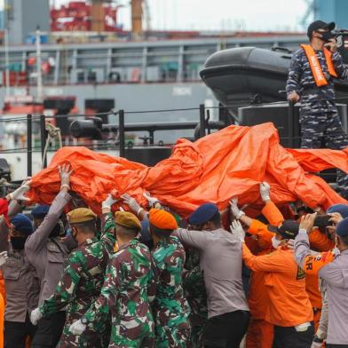 Rescue workers carry recovered debris at the port in Jakarta on January 10, 2021, during the search operation for Sriwijaya Air flight SJY182 which crashed after takeoff from Jakarta on January 9. (Photo by Dany Krisnadhi / AFP)<!-- NICAID(14687096) -->