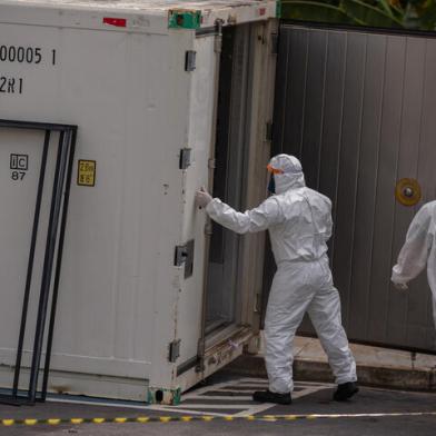 Health workers wear protective suits as they leave a body of a victim of the novel coronavirus in a refrigerated container at the Vinte Oito de Agosto Public Hospital, a unit treating COVID-19 patients in Manaus, Amazonas State, Brazil, on January 4, 2021. - The coronavirus has killed at least 1,843,631 people worldwide since the outbreak emerged in China in December 2019, according to an AFP tally on Monday based on official sources. The US is the worst-affected country with 351,590 deaths, followed by Brazil with 196,018. (Photo by Michael DANTAS / AFP)Editoria: HTHLocal: ManausIndexador: MICHAEL DANTASSecao: diseaseFonte: AFPFot¿grafo: STR<!-- NICAID(14687927) -->