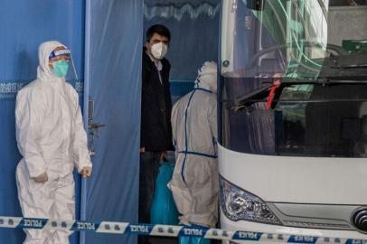 Vladimir G. Dedkov (C), a member of the World Health Organization (WHO) team investigating the origins of the Covid-19 pandemic, boards a bus following the teams arrival at a cordoned-off section in the international arrivals area at the airport in Wuhan on January 14, 2021. (Photo by NICOLAS ASFOURI / AFP)<!-- NICAID(14689976) -->