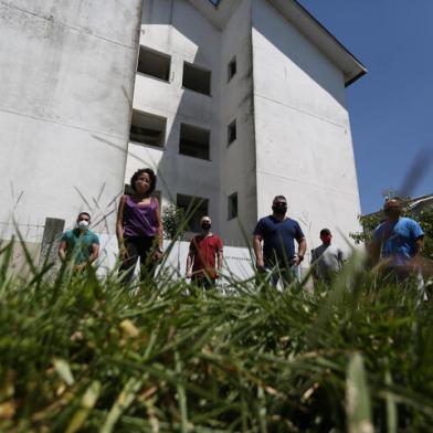 Gravataí, RS, BRASIL , 28/12/2020- Obras do Programa Minha casa minha vida estão parados na cidade de Gravataí, e causaram grande prejuízo a pessoas que investiram para ter a casa própria. Na foto (esq/dir):Osmar Flores, Édson Flores (verde), Tiago Fatturi de Souza(magrinho careca), Joyce Barcellos, Ricardo Mestre (óculos escuro), João Martins (boné), Hugo Martins (de azul).  Foto:  Jefferson Botega  / Agencia RBSIndexador: Jefferson Botega<!-- NICAID(14677780) -->