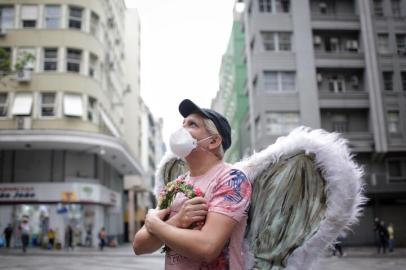 PORTO ALEGRE, RS, BRASIL, 22-03-2021: O artista argentino Abraham Ponce, que se apresenta como um anjo nas ruas de Porto Alegre, com as asas do personagem na Esquina Democrática. Ele está há pelos menos um ano longe das ruas. Mesmo sem ter o trabalho de artista de rua suspenso pelos decretos, preferiu se afastar por um motivo: os abraços das crianças. Perdeu amigos para a covid-19 e teme o vírus. Sem as apresentações, teve telefone cortado e conta com a renda do companheiro. (Foto: Mateus Bruxel / Agência RBS)Indexador: Mateus Bruxel<!-- NICAID(14740265) -->