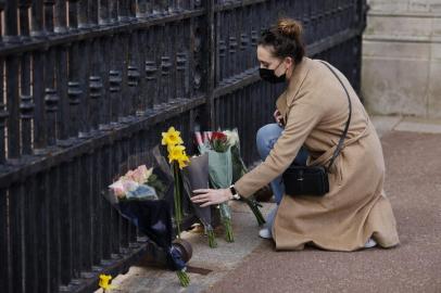 A woman lays a bunch of flowers at the gates of Buckingham Palace in central London on April 9, 2021 after the announcement of the death of Britains Prince Philip, Duke of Edinburgh. - Queen Elizabeth IIs husband Prince Philip, who recently spent more than a month in hospital and underwent a heart procedure, died on April 9, 2021, Buckingham Palace announced. He was 99. (Photo by Tolga Akmen / AFP)<!-- NICAID(14753914) -->