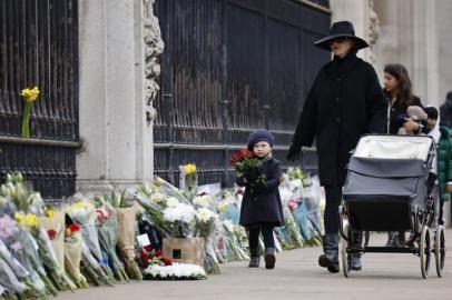 A child carries a floral tribute to Britains Prince Philip, Duke of Edinburgh outside Buckingham Palace, central London on April 10, 2021, the day after his death at the age of 99. - Military guns will be fired across Britain and sporting events will fall silent on Saturday as part of worldwide tributes to mark the death of Queen Elizabeth IIs husband, Prince Philip. (Photo by Tolga Akmen / AFP)<!-- NICAID(14754968) -->