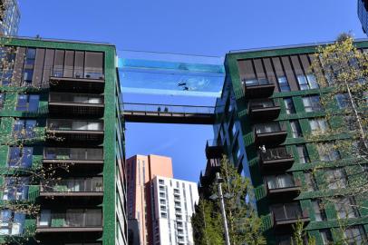 Models swim in a transparent acrylic swimming pool bridge that is fixed between two apartment blocks at Embassy Gardens next to the new US Embassy in south-west London on April 22, 2021. - A world first, the transparent 25-metre-long outdoor pool, known as the Sky Pool, will allow residents to swim from one building to the other, 10 storeys above the ground. (Photo by Justin TALLIS / AFP)Editoria: FINLocal: LondonIndexador: JUSTIN TALLISSecao: economy (general)Fonte: AFPFotógrafo: STF<!-- NICAID(14765119) -->