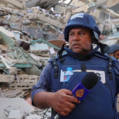 Al-Jazeera journalists stand next to the rubble of Jala Tower, which was housing international press offices, following an Israeli airstrike in the Gaza Strip on May 15, 2021. - An Israeli air strike demolished the 13-floor building housing Qatar-based Al-Jazeera television and American news agency The Associated Press in the Gaza Strip. (Photo by MOHAMMED ABED / AFP)<!-- NICAID(14784377) -->