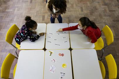 PORTO ALEGRE, RS, BRASIL, 10-05-2021: As alunas Clara Montardo Lima (E), 6 anos, e Valentina Silva Scola (D, de vermelho), 6, durante aula presencial da turma do primeiro ano do ensino fundamental com a professora Adriana Paza, na EMEF Neusa Goulart Brizola. Apenas duas alunas dos 19 estudantes da turma aderiram ao ensino presencial. (Foto: Mateus Bruxel / Agencia RBS)Indexador: Mateus Bruxel<!-- NICAID(14779275) -->