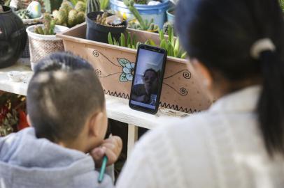 PORTO ALEGRE, RS, BRASIL, 26-04-2021: Davi Goncalves da Costa, 6 anos, realiza tarefas escolares com a ajuda da mae dele, Denise Carvalho Gonçalves, em casa, no loteamento Cavalhada. Em processo de alfabetizacao na Emef Neusa Goulart Brizola, o menino tem aulas com a professora Adriana Paza por videochamada. (Foto: Mateus Bruxel / Agencia RBS)Indexador: Mateus Bruxel<!-- NICAID(14766886) -->