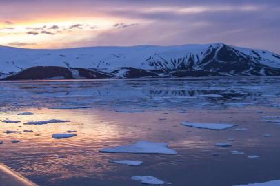 Arctic glow of summer sunset reflecting in Whaler Bay, Deception Island, Antarctica with deck of cruise ship.<!-- NICAID(14131466) -->