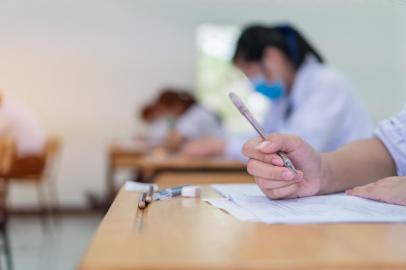 Asian Students testing in exam exercise taking at high school or university in test room. Hands hold pencil reading document paper on wooden desks classroom, Back to school for evaluation measurementFonte: 423526615<!-- NICAID(14793467) -->