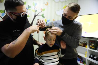 CACHOEIRINHA,RS,BRASIL.2021,06,17.Para atender filho autista, pai faz curso de barbearia e menino tem cabelo cortado em casaVamos mostrar o esforço de um pai que tem um filho autista. O garoto tem sensibilidade a ambientes barulhentos. No salão onde cortava o cabelo, se traumatizou, em um dia que presenciou outra criança chorando. O pai fez um curso de barbearia e passou a cortar o cabelo em casa, na cidade de cachoeirinha. O instrutor do curso disse nunca ter visto alguém com tamanho esforço para cortar o cabelo de um filho,pai Micheael Kratina e a mãe Gabriele Bernardo Vargas e o barbeiro Julio Slaski.(RONALDO BERNARDI/AGENCIA RBS).<!-- NICAID(14811183) -->