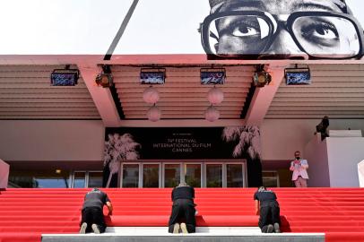 Festival staff roll the red carpet as the 74th edition of the Cannes Film Festival kicks off in southern France, on July 6, 2021. - The famed Cannes Film Festival opens on July 6, and despite social distancing subduing some of its signature glamour, excitement is rife for the first fully fledged film festival since the start of the coronavirus pandemic. (Photo by John MACDOUGALL / AFP)<!-- NICAID(14826787) -->