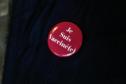 A man wears a badge that reads I am vaccinated at a restaurant in Deauville on July 27, 2021. - Frances highest constitutional authority said on July 26, 2021 it would rule next week on new legislation passed by parliament that would make vaccine passes a key part of daily life. (Photo by Sameer Al-DOUMY / AFP)<!-- NICAID(14845924) -->