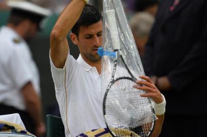 Serbias Novak Djokovic takes a fresh racquet from its wrapper in the break between games against Frances Adrian Mannarino during their mens singles second round match on the third day of the 2016 Wimbledon Championships at The All England Lawn Tennis Club in Wimbledon, southwest London, on June 29, 2016. Editoria: SPOLocal: LondonIndexador: GLYN KIRKSecao: tennisFonte: AFPFotógrafo: STR