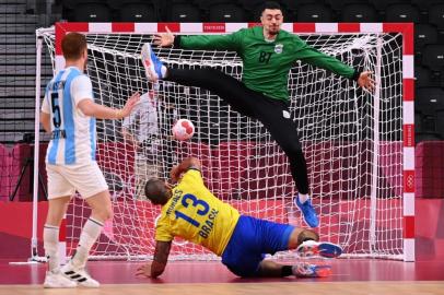 Brazils pivot Rogerio Moraes (C) shoots to score past Argentinas goalkeeper Juan Manuel Bar  during the mens preliminary round group A handball match between Argentina and Brazil of the Tokyo 2020 Olympic Games at the Yoyogi National Stadium in Tokyo on July 30, 2021. (Photo by Martin BERNETTI / AFP)<!-- NICAID(14849363) -->