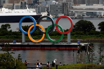 This photo taken on August 2, 2021 shows people posing for photos in front of the Olympic Rings near Tokyos Odaiba Marine Park, the venue for the triathlon at the 2020 Tokyo Olympic Games. (Photo by David GANNON / AFP)<!-- NICAID(14853077) -->