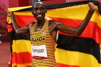 Ugandas Joshua Cheptegei celebrates with the national flag after winning the mens 5000m final during the Tokyo 2020 Olympic Games at the Olympic Stadium in Tokyo on August 6, 2021. (Photo by DYLAN MARTINEZ / POOL / AFP)<!-- NICAID(14855865) -->