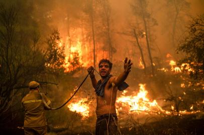 A local resident gestures as he holds n empty water hose during an attempt to extinguish forest fires approaching the village of Pefki on Evia (Euboea) island, Greeces second largest island, on August 8, 2021. - Hundreds of Greek firefighters fought desperately on August 8 to control wildfires on the island of Evia that have charred vast areas of pine forest, destroyed homes and forced tourists and locals to flee. Greece and Turkey have been battling devastating fires for nearly two weeks as the region suffered its worst heatwave in decades, which experts have linked to climate change. (Photo by ANGELOS TZORTZINIS / AFP)<!-- NICAID(14858651) -->