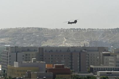 A US military helicopter is pictured flying above the US embassy in Kabul on August 15, 2021. (Photo by Wakil KOHSAR / AFP)<!-- NICAID(14862859) -->