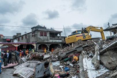 A bulldozer clears the rubble of a building that collapsed in the earthquake in Brefet, a neighborhood of Les Cayes, Haiti, on August 17, 2021. - The death toll from a 7.2 magnitude earthquake that struck Haiti has risen to 1,941, the Caribbean nations civil protection agency said Tuesday, as a tropical storm brought torrential downpours on survivors already coping with catastrophe.More than 9,900 people were wounded when the quake struck the southwestern part of the Caribbean nation on Saturday, about 100 miles (160 kilometers) to the west of the capital Port-au-Prince, according to the updated toll. (Photo by Reginald LOUISSAINT JR / AFP)<!-- NICAID(14866157) -->