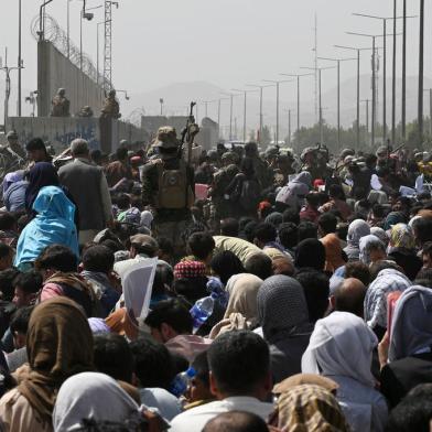 Afegãos se reúnem em uma estrada perto da parte militar do aeroporto de Cabul em 20 de agosto de 2021, na esperança de fugir do país após a tomada militar do Taleban no Afeganistão. (Foto de Wakil KOHSAR / AFP)<!-- NICAID(14868909) -->