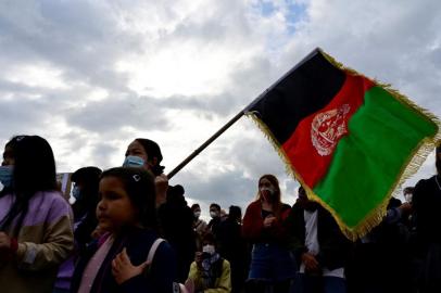 Participants wave the Afghan national flag as they demonstrate in front of the Reichstag building, seat of the German lower house of parliament Bundestag, in Berlin on August 17, 2021, to demand the safe passage and airlift out of Afghanistan, where people try flee the country after the Taliban swept back to power. (Photo by John MACDOUGALL / AFP)<!-- NICAID(14869644) -->