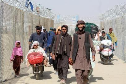 Afghan people walk inside a fenced corridor as they enter Pakistan at the Pakistan-Afghanistan border crossing point in Chaman on August 25, 2021 following the Talibans stunning military takeover of Afghanistan. (Photo by - / AFP)<!-- NICAID(14871416) -->