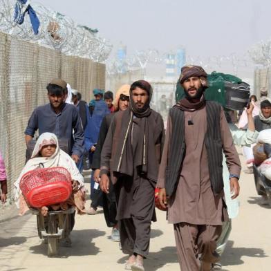 Afghan people walk inside a fenced corridor as they enter Pakistan at the Pakistan-Afghanistan border crossing point in Chaman on August 25, 2021 following the Talibans stunning military takeover of Afghanistan. (Photo by - / AFP)<!-- NICAID(14871416) -->