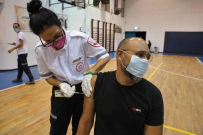 A paramedic with Israels Magen David Adom medical service administers the third shot of the Pfizer-BioNTech Covid-19 vaccine on August 24, 2021 in Holon. - Israel lowered the age threshold to receive a third coronavirus booster dose to anyone aged 30 and above, as it continues to battle surging infections. (Photo by AHMAD GHARABLI / AFP)<!-- NICAID(14876352) -->