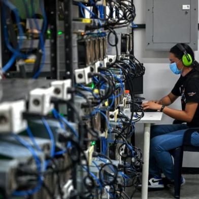 An employee inspects computers used to mine Bitcoins at the mining showroom of the Doctorminer company in Caracas on August 18, 2021. - In a Venezuela with ridiculously low electricity costs, mining cryptocurrencies has become a very profitable business, albeit a target for extortion. (Photo by Federico PARRA / AFP)<!-- NICAID(14876913) -->