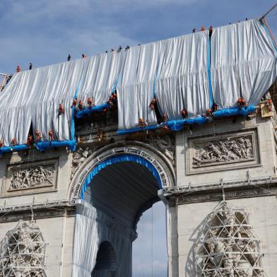 Workers unravel silver blue fabric, part of the process of wrapping LArc de Triomphe in Paris on September 12, 2021, designed by the late artist Christo. - Work has begun on wrapping the Arc de Triomphe in Paris in silvery-blue fabric as a posthumous tribute to the artist Christo, who had dreamt of the project for decades. Bulgarian-born Christo, a longtime Paris resident, had plans for sheathing the imposing war memorial at the top of the Champs-Elysees while renting an apartment near it in the 1960s. (Photo by Thomas SAMSON / AFP) / RESTRICTED TO EDITORIAL USE - MANDATORY MENTION OF THE ARTIST UPON PUBLICATION - TO ILLUSTRATE THE EVENT AS SPECIFIED IN THE CAPTION<!-- NICAID(14887544) -->