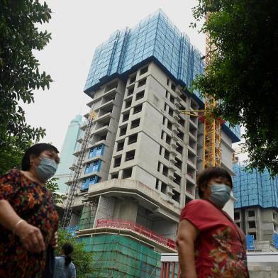 Pedestrians walk in front of an under construction Evergrande housing complex in Shenzhen, south-eastern China on September 16, 2021, as the Chinese property giant said it is facing unprecedented difficulties but denied rumours that it is about to go under. (Photo by Noel Celis / AFP)<!-- NICAID(14894310) -->