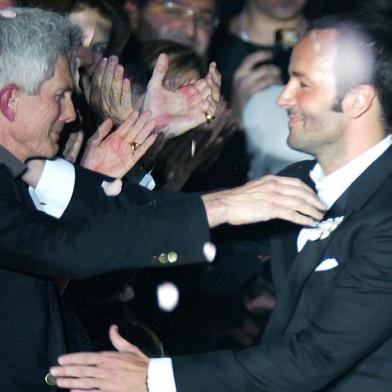 FASHION-ITALY-GUCCI-FORDUS designer Tom Ford (R) embraces his partner Richard Buckley, editor in chief of Vogue Hommes International as he acknowledges applause on the catwalk at the end of his last Gucci Autumn/Winter 2004-2005 women collection as part of the Milan fashion week 25 February 2004. (Photo by PATRICK HERTZOG / AFP)Editoria: ACELocal: MilanIndexador: PATRICK HERTZOGSecao: fashionFonte: AFP<!-- NICAID(14895004) -->