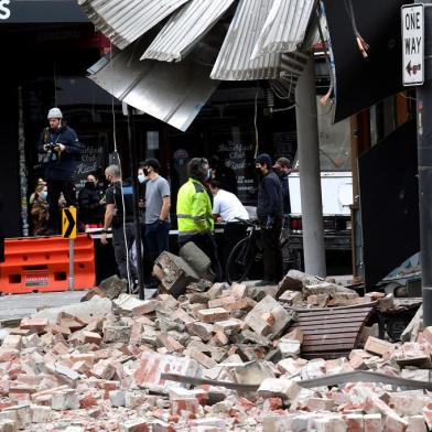 People gather near a damaged building in the popular shopping Chapel Street in Melbourne on September 22, 2021, after a 5.9 magnitude earthquake. (Photo by William WEST / AFP)<!-- NICAID(14895905) -->