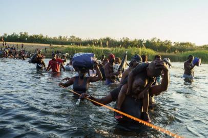 TOPSHOT - Haitian migrants continue to cross across the US-Mexico border on the Rio Grande as seen from Ciudad Acuna, Coahuila state, Mexico on September 20, 2021. - Migrant families sent back to Haiti by the United States after attempting to enter the country from Mexico are angry at their treatment and fearful of returning back home to a life punctuated by gang violence. The deportation of Haitian migrants had been temporarily suspended by Washington after a devastating earthquake hit the Caribbean nation last month.But in recent days, more than 15,000 Haitians crossed into the country from Mexico and found themselves stranded for days in Texas under a bridge spanning the Rio Grande river, blocked from moving onwards. (Photo by PAUL RATJE / AFP)<!-- NICAID(14895830) -->