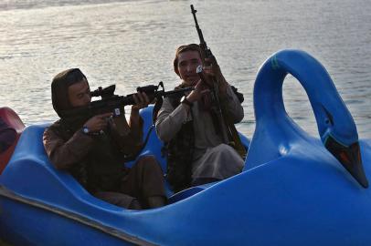 In this photograph taken on September 28, 2021 Taliban fighters ride on a paddle boat at Qargha Lake on the outskirts of Kabul. - This is Afghanistan! a Taliban fighter shouts on the pirate ship ride at a fairground in western Kabul, as his armed comrades cackle and whoop on board the rickety attraction. (Photo by WAKIL KOHSAR / AFP) / TO GO WITH: Afghanistan-conflict-fairground, SCENE by James EDGAREditoria: WARLocal: QarghahIndexador: WAKIL KOHSARSecao: leisure (general)Fonte: AFPFotógrafo: STF<!-- NICAID(14902169) -->