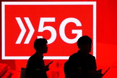 People walk past a 5G hotspot sign at the Mobile World Congress (MWC) in Barcelona on February 26, 2019. - Phone makers will focus on foldable screens and the introduction of blazing fast 5G wireless networks at the worlds biggest mobile fair as they try to reverse a decline in sales of smartphones. (Photo by Josep LAGO / AFP)Editoria: FINLocal: BarcelonaIndexador: JOSEP LAGOSecao: telecommunication equipmentFonte: AFPFotógrafo: STR<!-- NICAID(14902915) -->