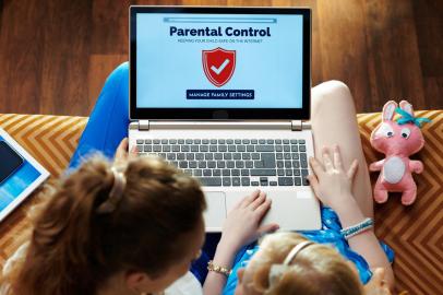 mother and daughter setting up parental control on laptopmodern mother and daughter sitting on sofa in the modern living room setting up parental control on a laptop.Fonte: 277584916<!-- NICAID(14921368) -->