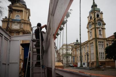 Equipes trabalham na montagem da 67ª edição da Feira do LivroNa tarde deste sábado (23), pelo menos 15 das 56 bancas da Feira do Livro desde ano já haviam sido montadas na Praça da Alfândega, no centro de Porto Alegre. Além de montar os espaços, a equipe também trabalha para levantar a estrutura da cobertura, que irá proteger o público em dias de chuva. O trabalho começou na última semana e deve ser concluído na próxima quarta-feira (27), quando os livreiros poderão começar a ocupar os locais. Em formato híbrido, a 67ª edição do evento começará na sexta-feira (29) e segue até o dia 15 de novembro.<!-- NICAID(14923210) -->