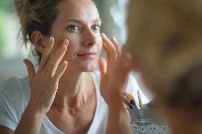 Portrait of woman looking at her face in mirrorFonte: 294362865<!-- NICAID(14910103) -->