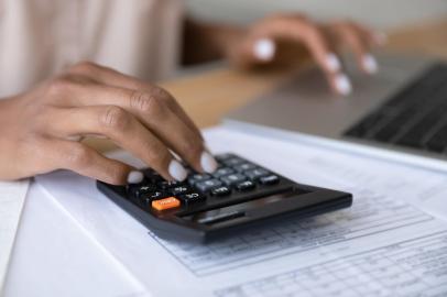 Close up of woman manage finances using laptopCrop close up of biracial woman calculate expenses expenditures on calculator machine, pay bills taxes online on computer. African American female manage budget on laptop. Saving, finance concept.Fonte: 425241195<!-- NICAID(14938560) -->