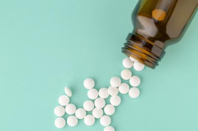 White round tablets scattered near glass bottle of pillsPORTO ALEGRE, RS, BRASIL,24/10/2019- Comprimidos redondos brancos espalhados. (Foto: ironstealth / stock.adobe.com)Indexador: A.KhoruzhenkoFonte: 290067398<!-- NICAID(14302401) -->