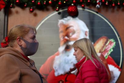 A pedestrian wearing a face coving to stop the spread of Covid-19, walks past an image of Santa Claus at a Christmas Market in central London on November 29, 2021. - Britain will require all arriving passengers to isolate until they can show a negative PCR test against Covid-19 and is restoring a mandate to wear face masks in shops and public transport as part of its response to the new Omicron strain of Covid-19. (Photo by Adrian DENNIS / AFP)<!-- NICAID(14953627) -->