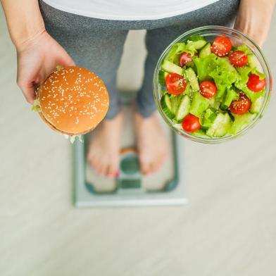 Dieting concept, beautiful young woman choosing between healthy food and junk foodPORTO ALEGRE, RS, BRASIL, dieta, vida saudavel, salada, (Foto: Maksymiv Iurii  / stock.adobe.com)Fonte: 274880218<!-- NICAID(14329111) -->