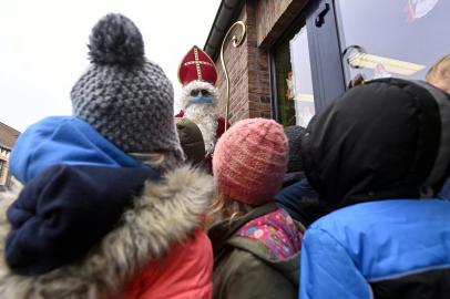 ¿Sinterklaas¿ (São Nicolau) recebe alunos de uma escola primária em Helecine, a 6 de dezembro de 2021 a partir de hoje, as crianças a partir dos seis anos devem usar máscara facial em espaços públicos, incluindo escolas. - A obrigação da máscara facial faz parte de novas e mais fortes medidas de segurança e saneamento na contínua pandemia de Covid-19 na Holanda. (Foto de ERIC LALMAND / BELGA / AFP) / Bélgica OUT<!-- NICAID(14968502) -->