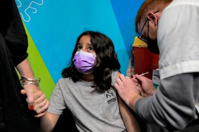 An Israeli health worker administers a dose of the Pfizer/BioNTech Covid-19 vaccine to an eight-year-old child at Clalit Health Services in Jerusalem on November 23, 2021, as Israel begins coronavirus vaccination campaign for children aged five to 11. - Israel on November 14 gave the green light to start vaccinating children aged between five and 11 against Covid-19 using Pfizer/BioNTech jabs, following the example of the United States. It was one of the first countries to launch a vaccination campaign last year using the jabs thanks to a deal with Pfizer that gave it access to millions of doses in exchange for data on the vaccines efficacy. (Photo by MENAHEM KAHANA / AFP)Editoria: HTHLocal: JerusalemIndexador: MENAHEM KAHANASecao: diseaseFonte: AFPFotógrafo: STF<!-- NICAID(14948788) -->